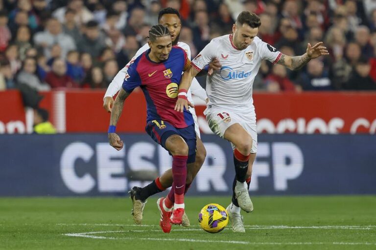 El delantero del Barcelona Raphinha (i) pelea un balón con Saúl Ñíguez, del Sevilla, durante el partido de LaLiga de fútbol que Sevilla FC y FC Barcelona disputaron en el estadio Ramón Sánchez-Pizjuán. EFE/ José Manuel Vidal