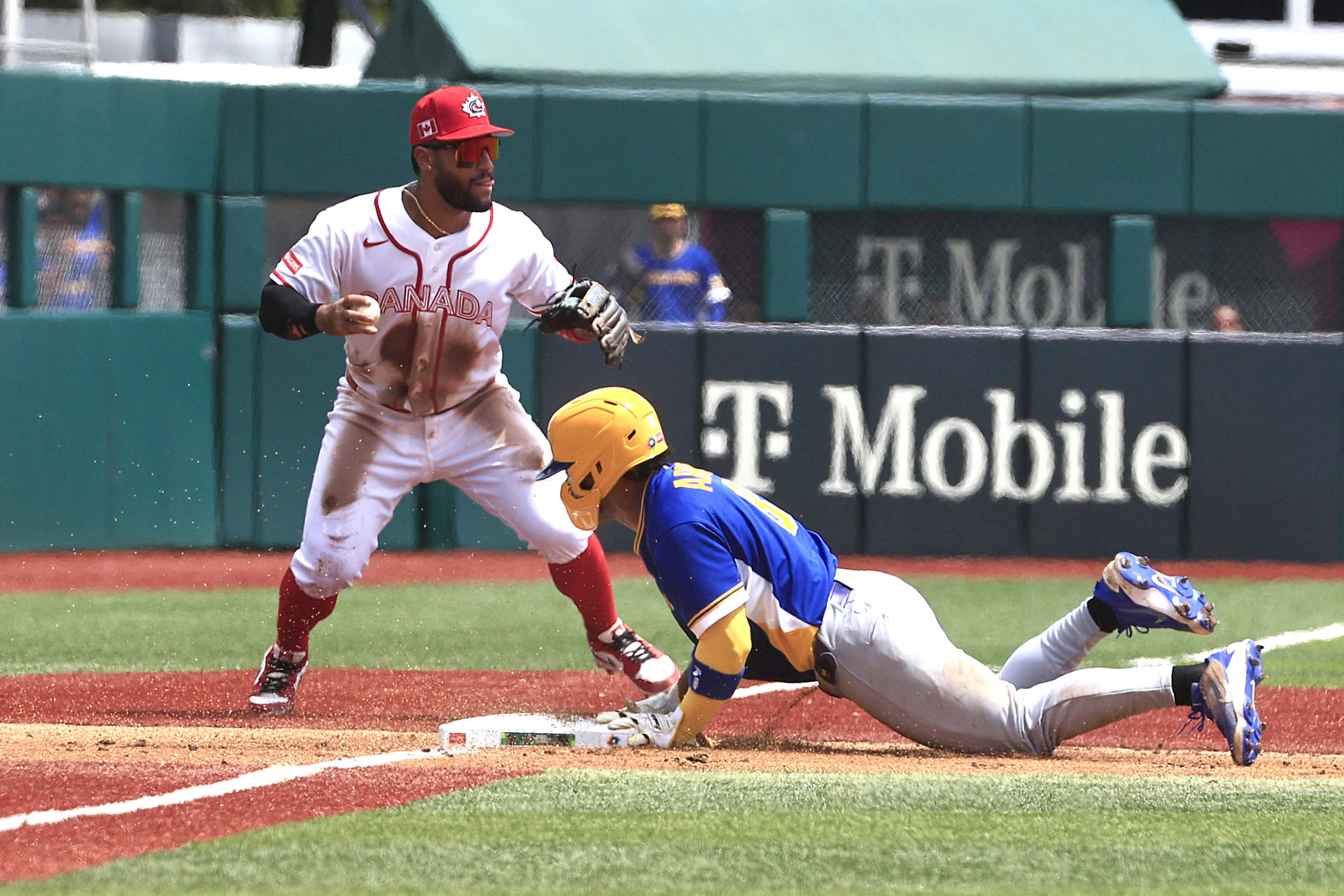 El colombiano Michael Arroyo (d) se desliza en tercera base ante el canadiense Abraham Toro durante el juego del Clásico Mundial de Béisbol de este sábado en el estadio Hiram Bithorn de San Juan. EFE/ Thais Llorca
