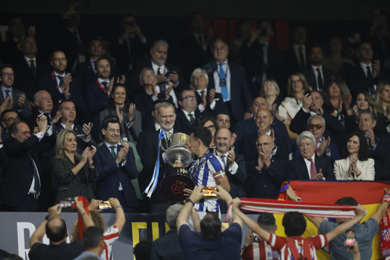 El capitán de la Real Sociedad Mikel Oyarzabal (c) recibe el trofeo de manos de su majestad el Rey tras la final de la Copa del Rey que han disputado frente al Atlético de Madrid este sábado en el estadio de La Cartuja, en Sevilla. EFE/Julio Muñoz.