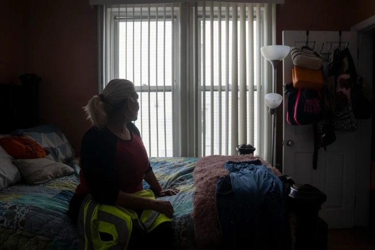 Maribel Urbina, inmigrante hondureña, se sienta en su cama con el chaleco que usaba como conductora de autobús escolar el martes 31 de marzo de 2026. Urbina, quien fue conductora de autobús escolar durante 21 años, perdió su Estatus de Protección Temporal y su autorización de trabajo cuando la administración Trump canceló el programa para los hondureños. Por motivos de privacidad, Urbina prefirió no publicar su rostro. Foto Julian Leshay Guadalupe/NorthJersey.com