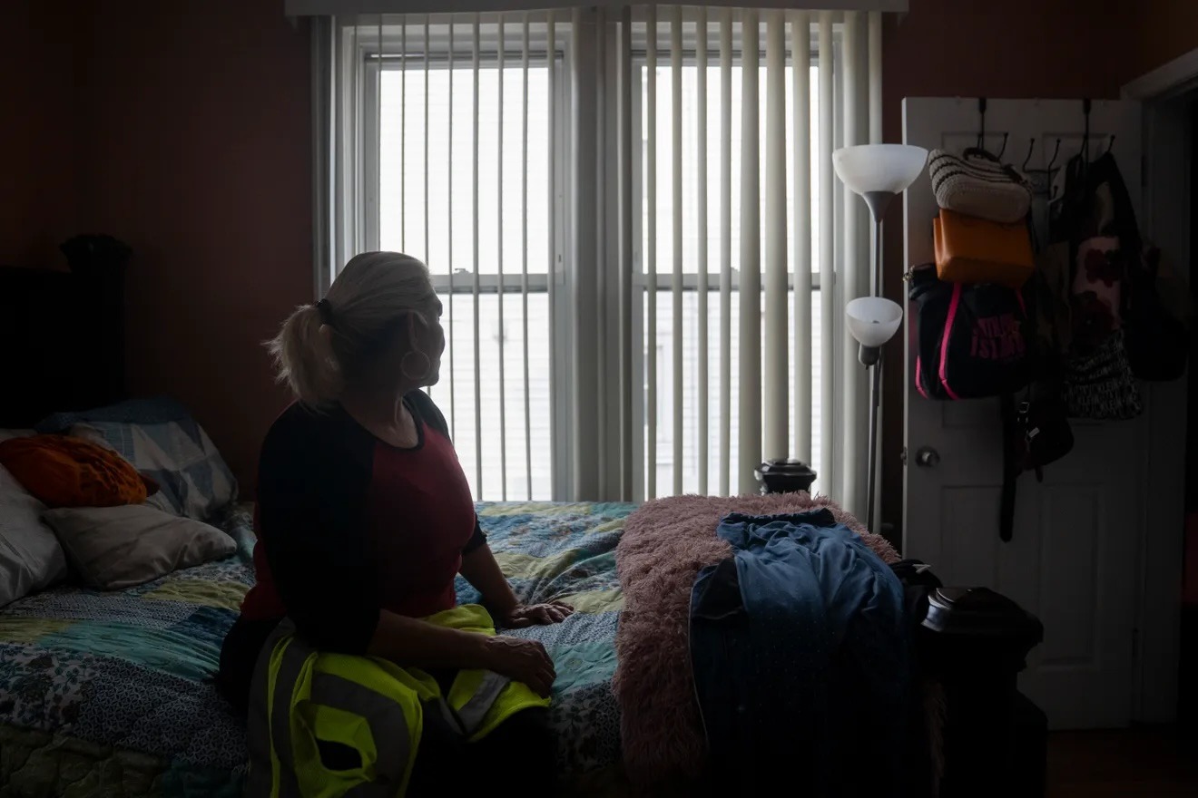 Maribel Urbina, inmigrante hondureña, se sienta en su cama con el chaleco que usaba como conductora de autobús escolar el martes 31 de marzo de 2026. Urbina, quien fue conductora de autobús escolar durante 21 años, perdió su Estatus de Protección Temporal y su autorización de trabajo cuando la administración Trump canceló el programa para los hondureños. Por motivos de privacidad, Urbina prefirió no publicar su rostro. Foto Julian Leshay Guadalupe/NorthJersey.com
