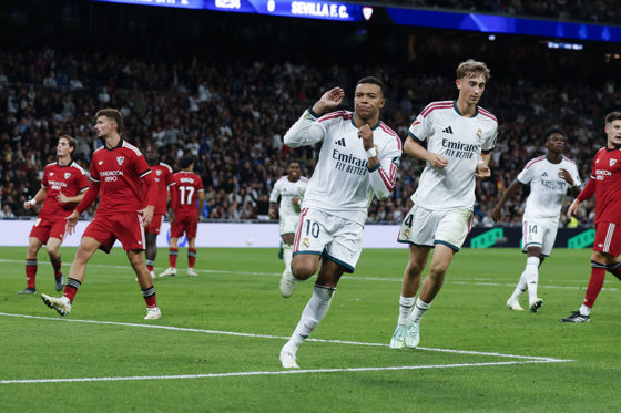 El delantero francés del Real Madrid Kylian Mbappé (c) celebra su segundo gol durante el partido de la jornada 9 de LaLiga entre el Real Madrid y el Sevilla FC, este domingo en el estadio Santiago Bernabéu. EFE/J.J.Guillén