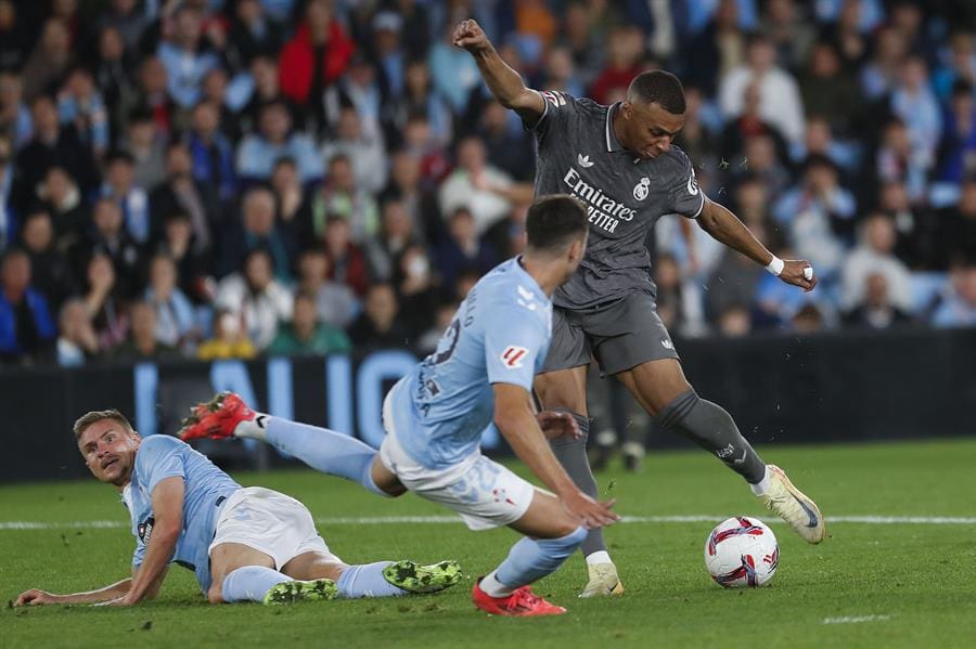 Real Madrid's forward Kylian Mbappé (R) prepares to shoot against Celta's Javier Manquillo (C) during a LaLiga match between Celta de Vigo and Real Madrid at Vigo's Balaidos stadium in Pontevedra, Spain, 19 October 2024. EFE/ Salvador Sas