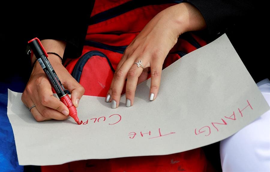 A lawyer writes on a placard as she takes part in a signature campaign seeking justice in a rape and murder case in Srinagar, India, 18 April 2018. EPA/FAROOQ KHAN