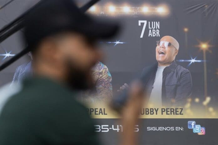 A man talks on the phone next to an image of the late merenguero Rubby Perez on Wednesday, in Santo Domingo, Dominican Republic. Apr. 9, 2025. EFE/ Orlando Barría