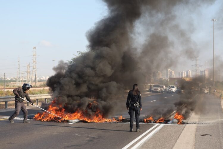 Israeli police officers work to extinguish burning tires set on fire by protesters on the main road connecting Tel Aviv and Jerusalem, Israel, 17 August 2025. EFE-EPA/ABIR SULTAN