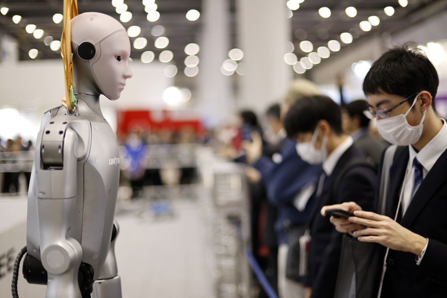 A visitor stands next to a humanoid robot at the TechShare booth during the International Robot Exhibition 2025 (iREX2025) in Tokyo, Japan, 03 December 2025. EFE/EPA/FRANCK ROBICHON