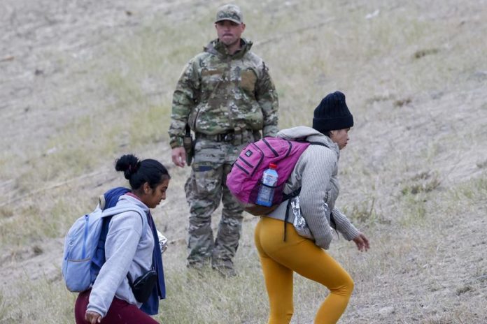 (FILE)- Un miembro de la Guardia Nacional de Texas (C) observa cómo los migrantes suben la colina en Shelby Park, en Eagle Pass, Texas, EE. UU., el 21 de diciembre de 2023. EFE/EPA/Adam Davis
